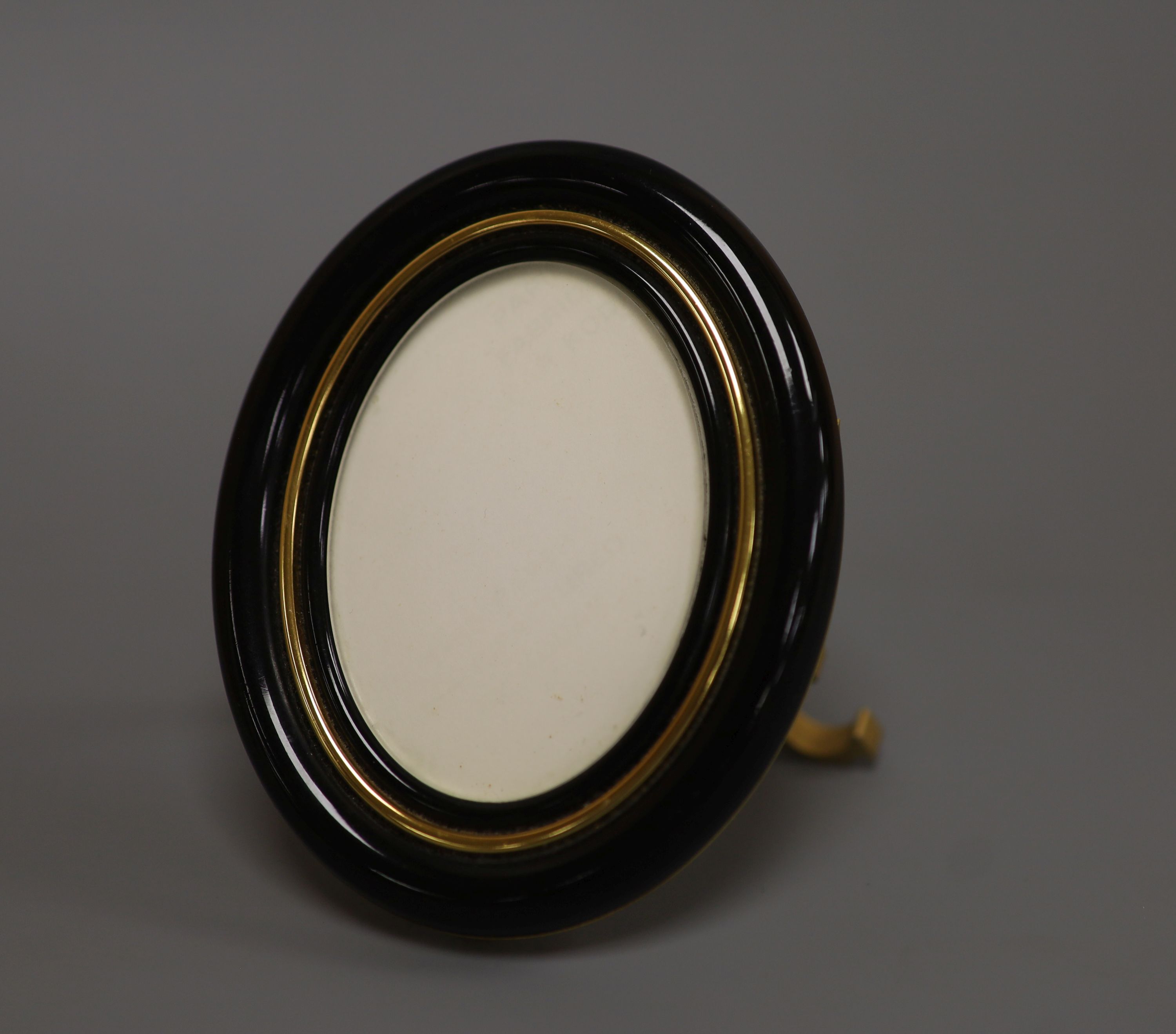 A Must de Cartier black lacquered and gilt oval easel photograph frame, length 9cm